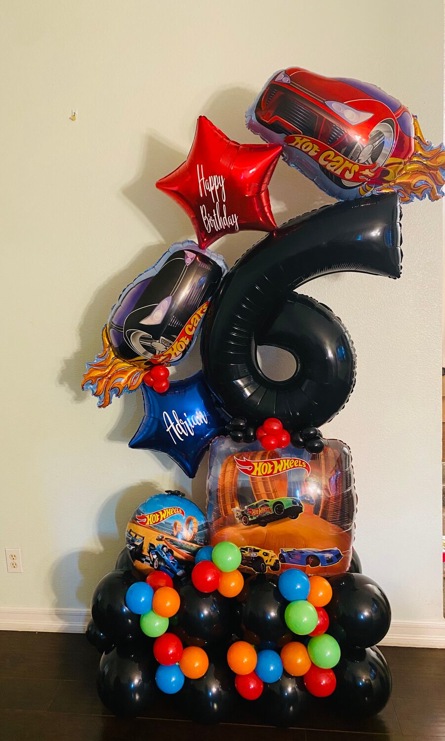 Red, black and gold number 6 balloon tower with race car foils