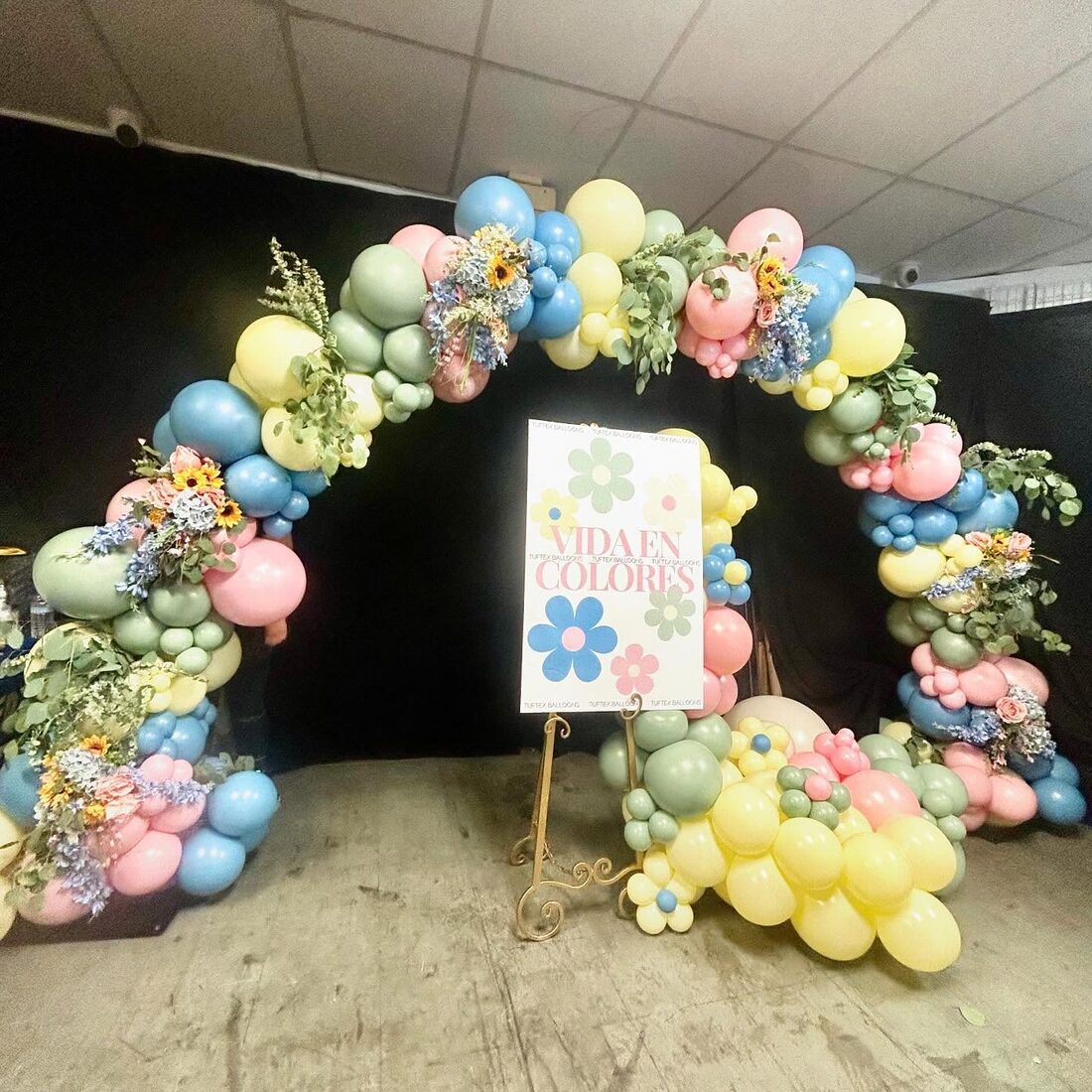 Pastel balloon arch with flowers around a welcome sign