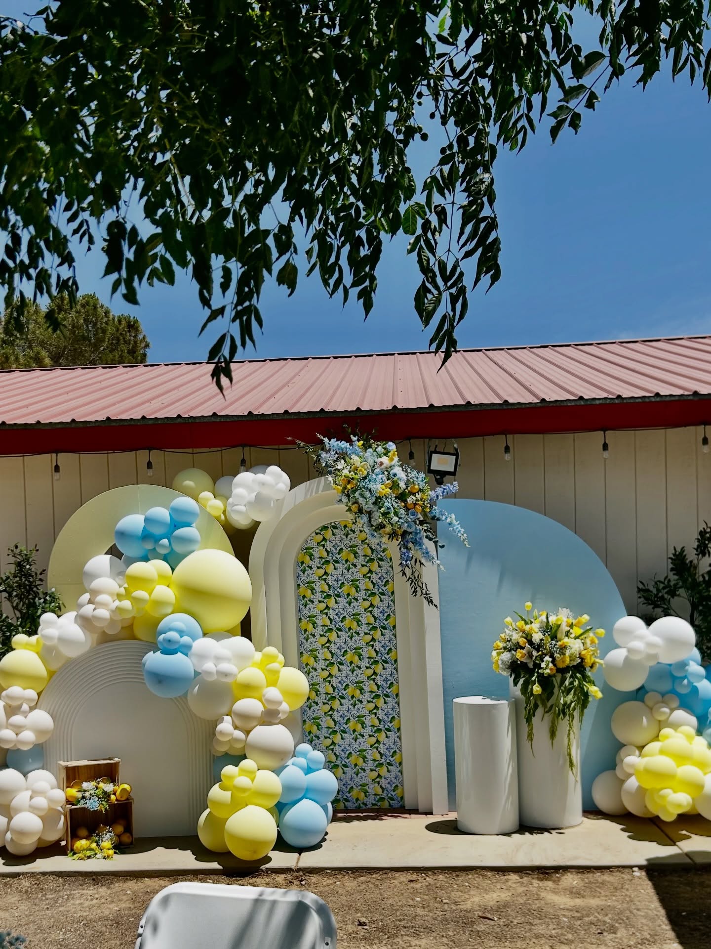 White, butter and sky blue balloon arch around a patterned doorway outdoors