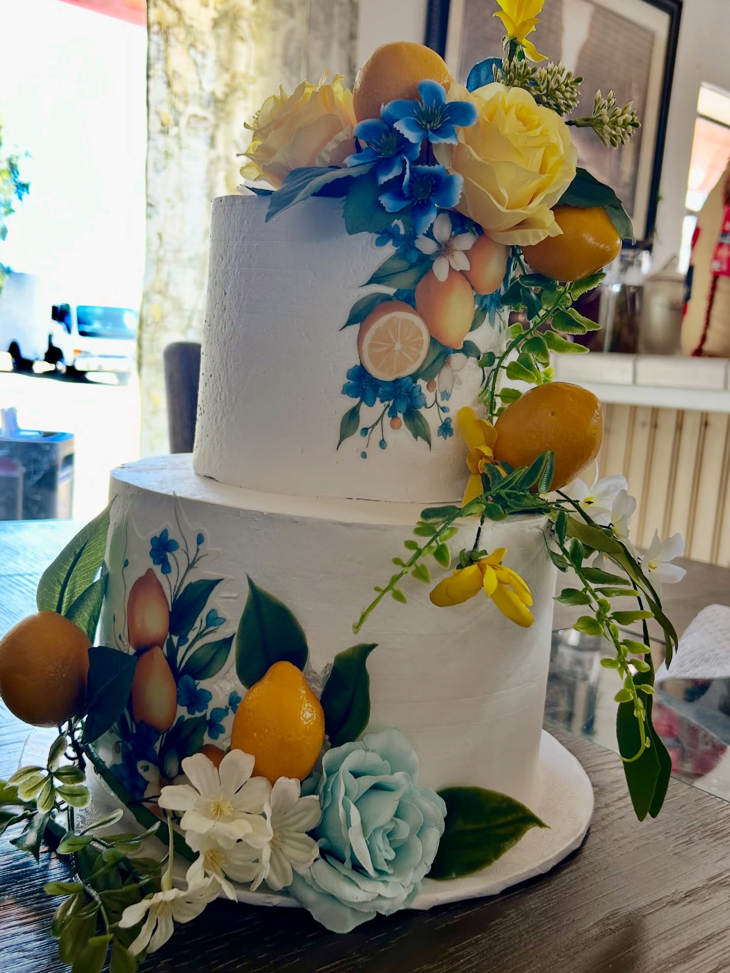White tiered cake dressed with lemons and blue flowers